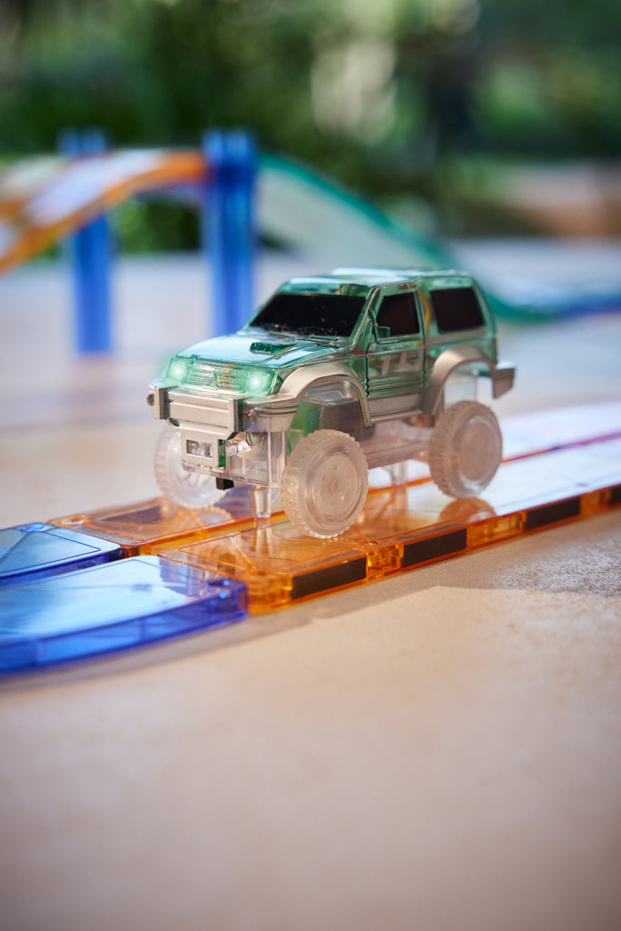 Auto magnetica verde Cleverclixx in movimento sulla pista luminosa