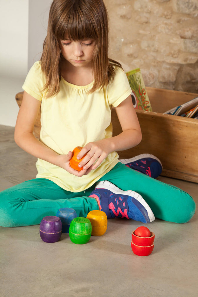 Bambina impegnata a ordinare ciotole e sfere colorate Grapat, attività di classificazione e coordinazione.