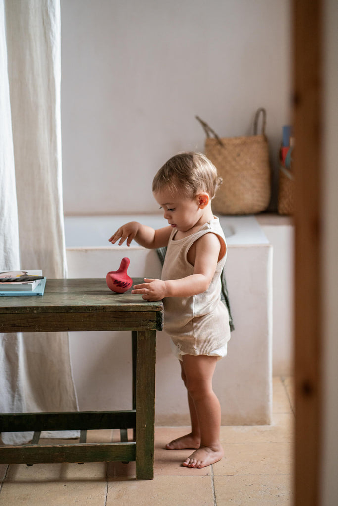 Bambino che gioca in piedi con il Grapat Chill Pink Bird, giocattolo in legno artigianale