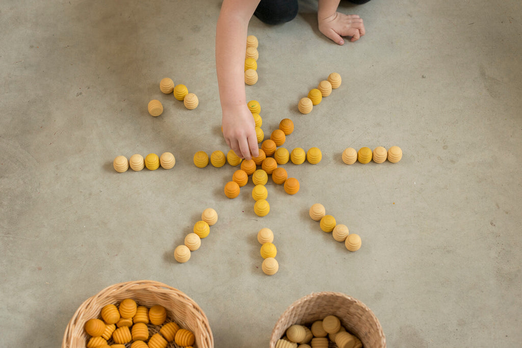 Bambino che dispone gli alveari in legno del set Grapat Mandala Honeycomb in una composizione a raggiera.