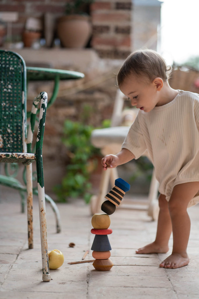 Bambino che osserva la torre del Grapat Serendipity, gioco di costruzione in legno colorato