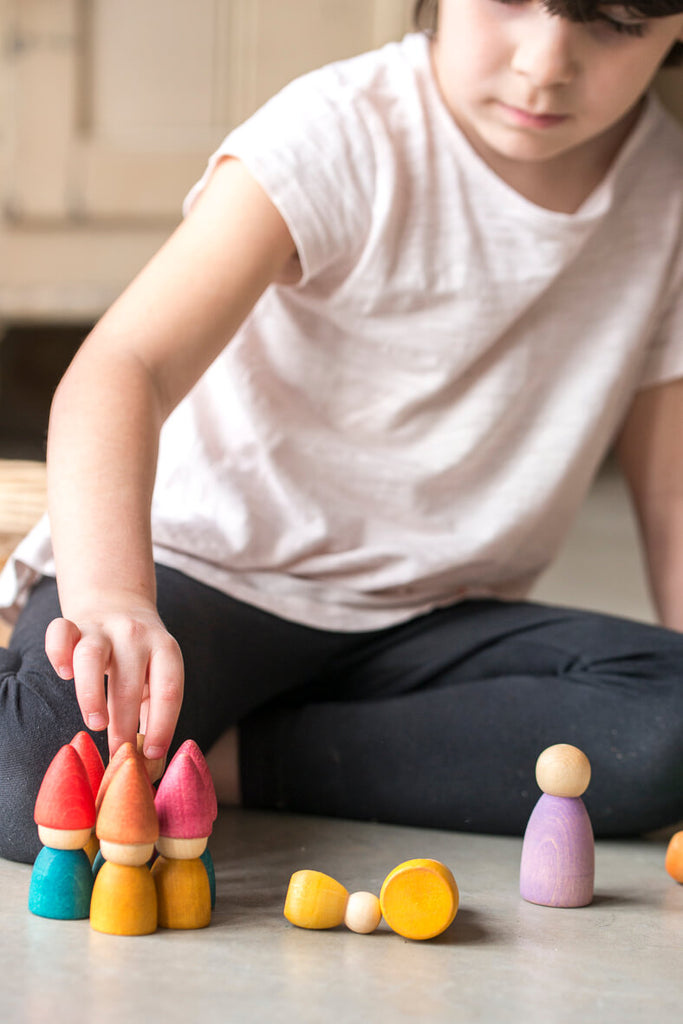 Bambina che gioca con le figure in legno Grapat Tomtens seduta a terra