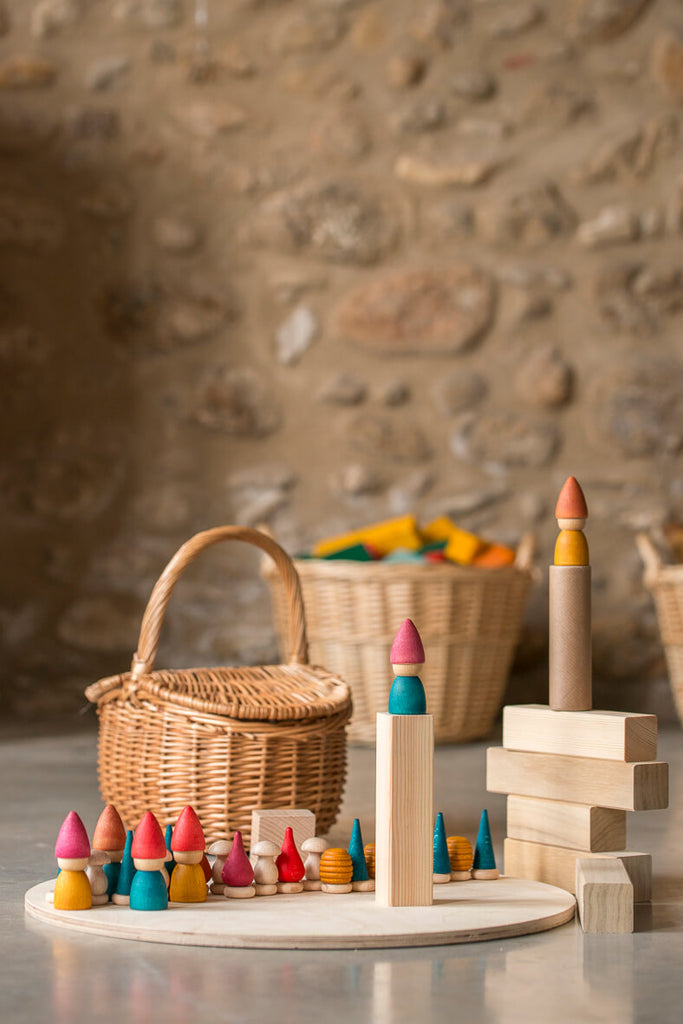Grapat Tomtens: figure in legno colorate disposte su una base con blocchi e cestini sullo sfondo.