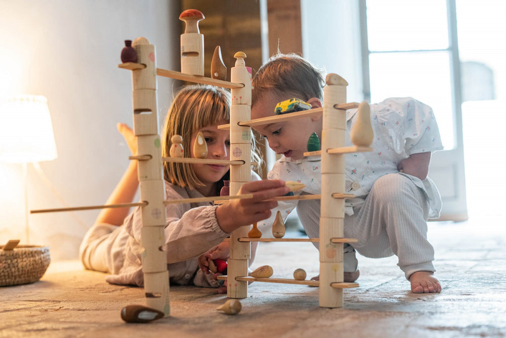 Bambini che giocano insieme con il set Grapat Woodland, costruzione in legno naturale su pavimento di casa